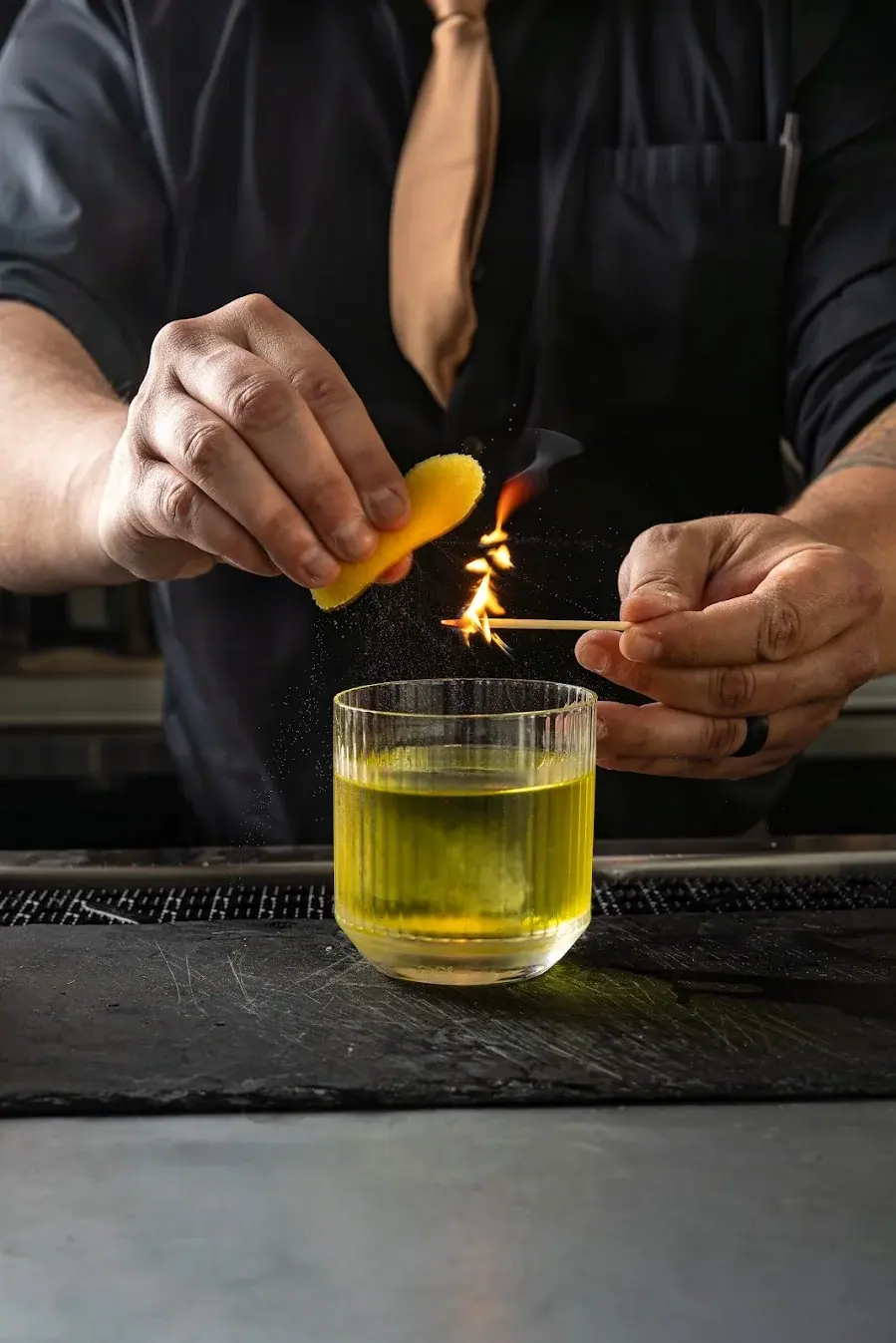 An orange twist flamed over a cocktail
