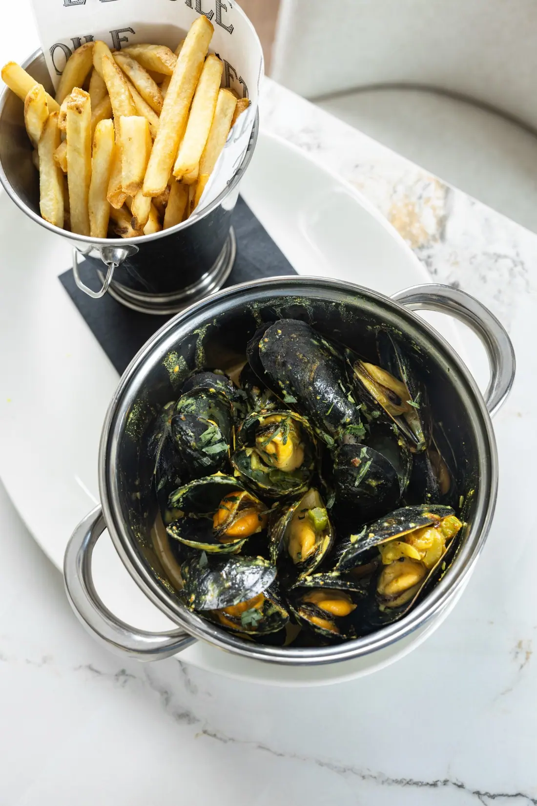 A pot of mussels beside a basket of frites