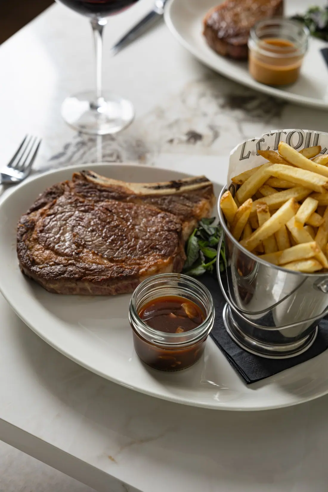 Steak frites with a glass of red on the marble